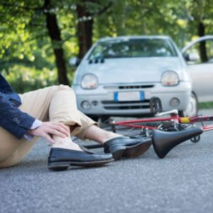 A man lying on the ground next to his bike and car - Levian Law