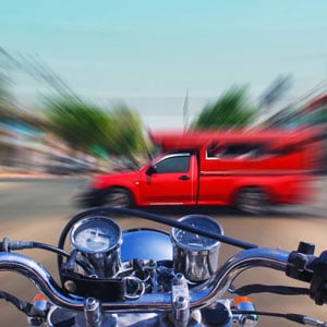 A motorcycle speeding on the road toward red truck - Levian Law