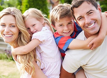 A smiling family on the grassy ground - Levian Law