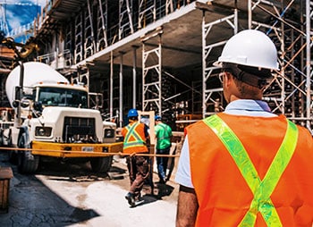 A group of construction workers in orange vests and helmets - Levian Law